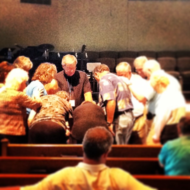 Bishop Bill McAlilly leads prayer over one who has shared her GodStory.